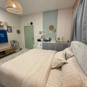 a bedroom with a large white bed and a kitchen at The Italian Studio7 in Dammam