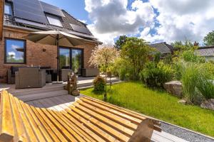 a backyard with a wooden bench and an umbrella at Püppi Hems Huus in Osterhever