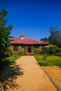 a house with a red roof and a dirt road at MF Holiday Bungalow in Bandarawela