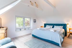 a bedroom with a blue bed and two windows at Püppi Hems Huus in Osterhever