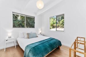 a white bedroom with a bed and two windows at The Loft at Long Beach in Long Beach