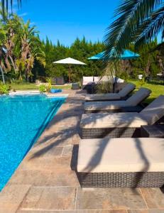 a pool with lounge chairs and umbrellas next to it at Chambre d'hôtes in Ondara
