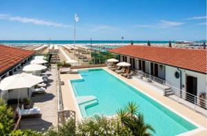 a swimming pool with umbrellas and the beach at Hotel Club I Pini - Boutique Hotel & Residenza d'Epoca in Lido di Camaiore