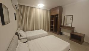a hotel room with two beds and a mirror at Salalah Royals Residence in Daḩārīz