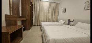 a hotel room with two beds and a desk at Salalah Royals Residence in Daḩārīz