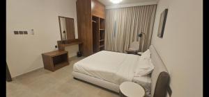 a bedroom with a bed and a table and a lamp at Salalah Royals Residence in Daḩārīz