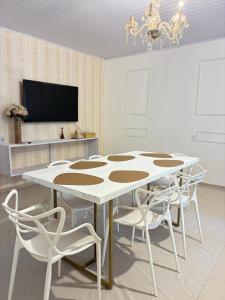 a dining room with a white table and chairs at Jardim Florestal Italy-Casa Jacarandá in Itaquatiara