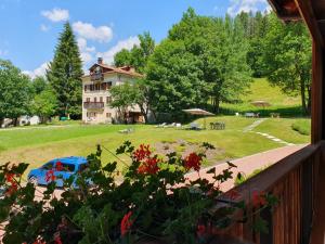 a house with a blue car in front of a yard at Hotel Orso Grigio in Selva di Cadore