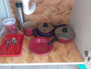 a table with pots and pans on a wooden floor at Casinha da Alê in Mongaguá