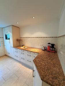 a kitchen with white cabinets and a granite counter top at Alpenzeit - Ferienhaus mit Sauna, Garten und Bergblick bei Garmisch-Partenkirchen in Farchant