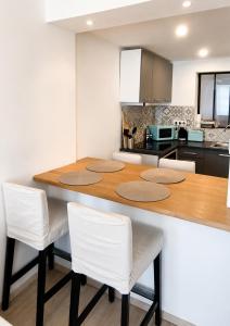 a kitchen with a wooden table and white chairs at Home Dream/Erstein/3P/60m2 in Erstein