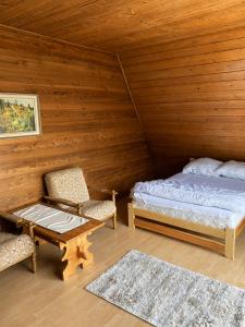 a bedroom with a bed and a chair in a room at Pogórzański Domek in Ciężkowice
