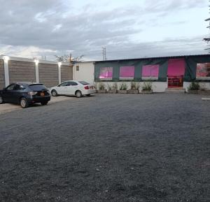 two cars parked in a parking lot in front of a building at J & J Olosho Hotel in Kiserian +3 photos