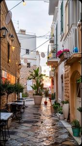 an alley in a town with tables and potted plants at La Maison in Trani