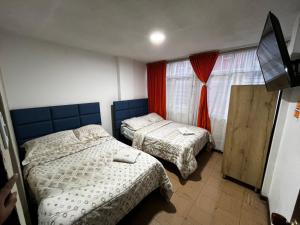 a bedroom with two beds and a tv and a window at Hotel Inkanta in Ipiales