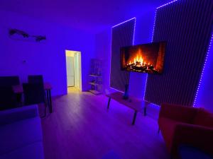 a living room with a fireplace and purple lighting at City Line Koblenz in Koblenz