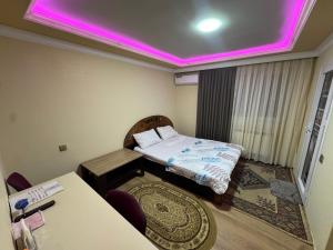 a room with a bed and a table with a purple light at Elit Hotel in Mingachevir