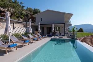 a pool with lounge chairs and umbrellas next to a house at Zofeni in Póndi