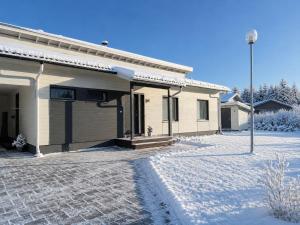 a house with snow on the ground in front of it at Villa Lydia Lapland - Private Sauna & Aurora View in Rovaniemi