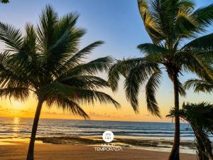 two palm trees on the beach at sunset at Casa Ilha do Sol - Vera Cruz/BA in Vera Cruz de Itaparica