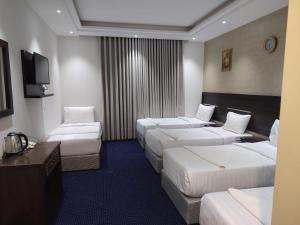 a hotel room with four beds and a flat screen tv at فندق نمبر وان 3 in Al Masfalah
