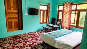 a bedroom with a bed and a chair and windows at Alpine Hub Gurez in Wāmpor