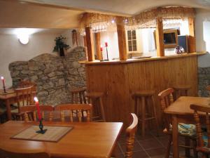 a restaurant with a bar and wooden tables and chairs at Penzion u Antošů in Jeseník