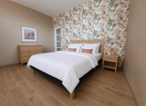 a bedroom with a large white bed and a floral wallpaper at Cap Ouest in Fécamp