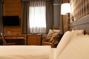 a hotel room with a bed and a desk with a computer at Hotel Orso Grigio in Selva di Cadore