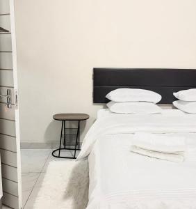 a bedroom with a bed with white sheets and a stool at Ekhaya Loft in Mbabane