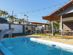 a swimming pool with a fountain in a yard at HOSTEL QUINTAL GUEST - Guarujá in Guarujá
