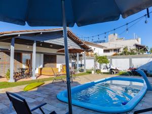 a swimming pool with an umbrella in a yard at HOSTEL QUINTAL GUEST - Guarujá in Guarujá