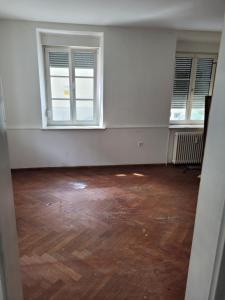an empty room with two windows and a wooden floor at Simple Übernachtungsmöglichkeit in Krumbach