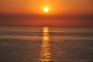 an orange sunset over the ocean with the sun setting at Apartamentos Guillem in Playa de Miramar