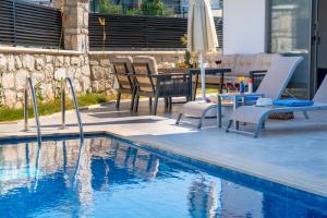a swimming pool with chairs and a table next to it at Villa Kaş B in Kaş