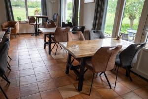 a dining room with tables and chairs and windows at Boerderij "De Verwondering" in Goudriaan