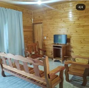 a living room with a couch and a television in a log cabin at Quinta Bommerl in Paso de la Patria