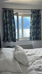 a bedroom with a bed and a window with a view at Ferienhaus mit Privatgarten in Gambarogno +3 photos