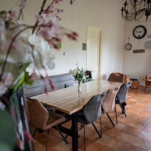 a dining room table with chairs and a vase of flowers at Boerderij "De Verwondering" in Goudriaan +29 photos