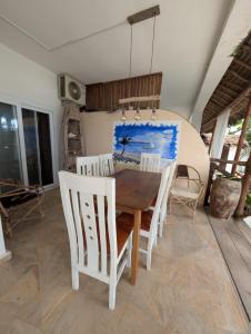 a dining room with a wooden table and chairs at Thamani Apartment Zanzibar in Pwani Mchangani +11 photos