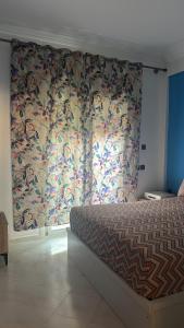 a bedroom with a bed and a curtain with flowers at Stodio sofia in Essaouira