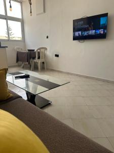 a living room with a glass coffee table and a tv at Stodio sofia in Essaouira