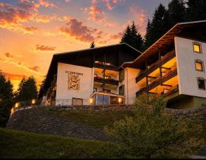 a building on a hill with a sunset in the background at Hotel Haus Sonnblick in Bad Kleinkirchheim