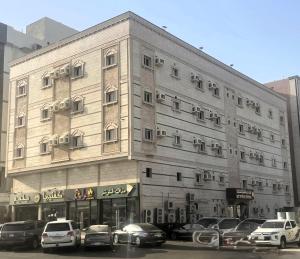 a large building with cars parked in a parking lot at Best Trip Marsilia Served Apartments in Jeddah
