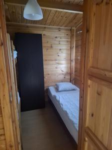 a small room with a bed in a wooden cabin at Domki na Wyspie Anna in Gdańsk