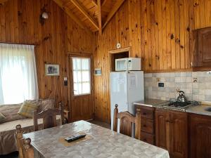 a kitchen with a refrigerator and a table in a room at Illihue - Cabañas, Hostería & Spa in Junín de los Andes