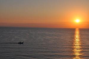 a boat in the ocean at sunset at Apartamentos Guillem in Playa de Miramar