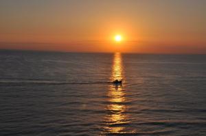 a boat in the ocean at sunset at Apartamentos Guillem in Playa de Miramar
