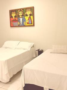 two beds in a room with a painting on the wall at AP 06 - Apartamento Estudio completo in Balsas