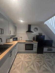 a kitchen with white cabinets and a sink at Cosy Moat House Cottage #2 in Pembroke +1 photo